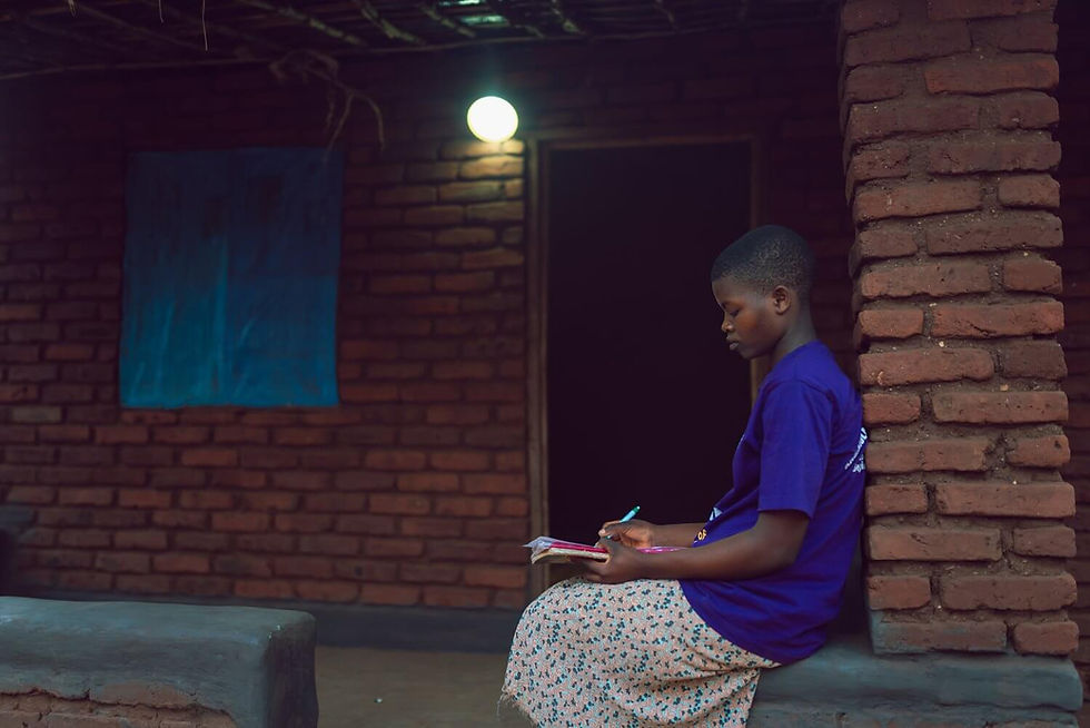 A young woman studies by solar-powered electric light, a far better and healthier way than using candle or kerosene light, both of which are not only inefficient and polluting but expensive. Courtesy of SolarAid/Kondwani Jere