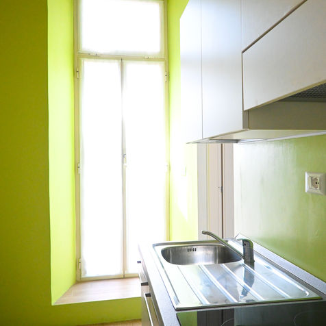 A modern, fully equipped green kitchen at Casa Pesa, featuring all the essential appliances for a convenient and enjoyable stay. The space is complemented by a stylish dining table with 60s-inspired designer chairs, creating the perfect atmosphere for meals and gatherings. Whether you're cooking a home-made meal or enjoying a vibrant holiday home experience, this apartment in Pigneto Rome provides a unique and functional setting for your Rome holidays.