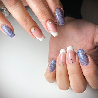 Ricostruzione in gel con due dita french con applicazioni glitter e le altre unghie con glitter sottili su base azzurra.