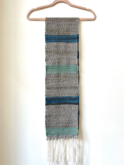 a handwoven scarf with cool tones and white tassels