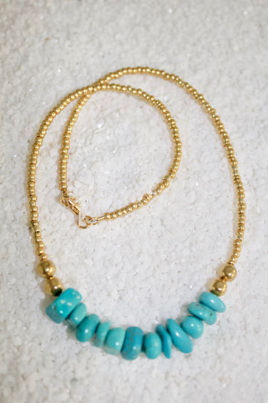 a necklace with turquoise beads and a gold chain