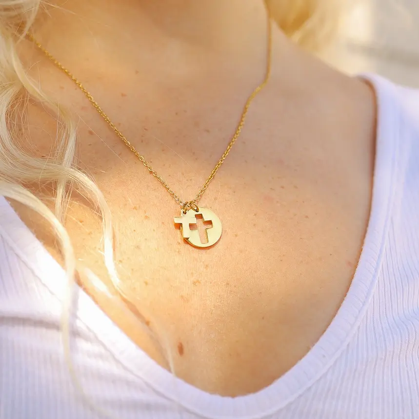 Woman wearing a gold cross necklace and white shirt
