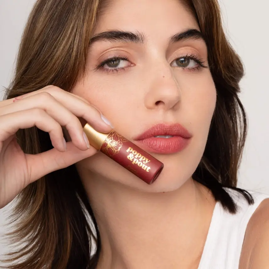 Thumbnail: Young woman holding a tube of lip gloss
