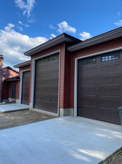 Exterior view of a red three-car garage and new cement driveway under construction in Leominster, MA