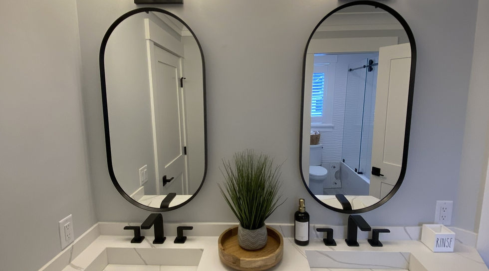 White double bathroom vanity with black fixtures and framed mirrors