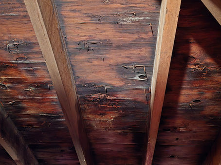 Delaminating roof decking with organic growth on the underside caused by trapped attic moisture and poor roof ventilation in Westminster Massachusetts