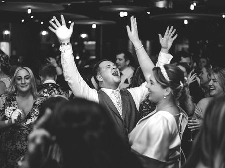 Groom celebrating with arms raised on the dance floor during wedding reception at Hencote Vineyard, surrounded by guests in a lively party atmosphere.