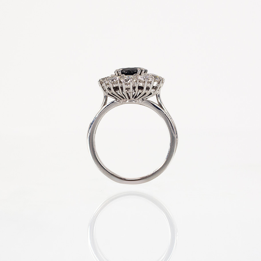 ANELLO IN ORO BIANCO FORMA A ROSETTA CON DIAMANTI E ZAFFIRO CENTRALE PERFETTO COME ANELLO DI FIDANZAMENTO ALTERNATIVO