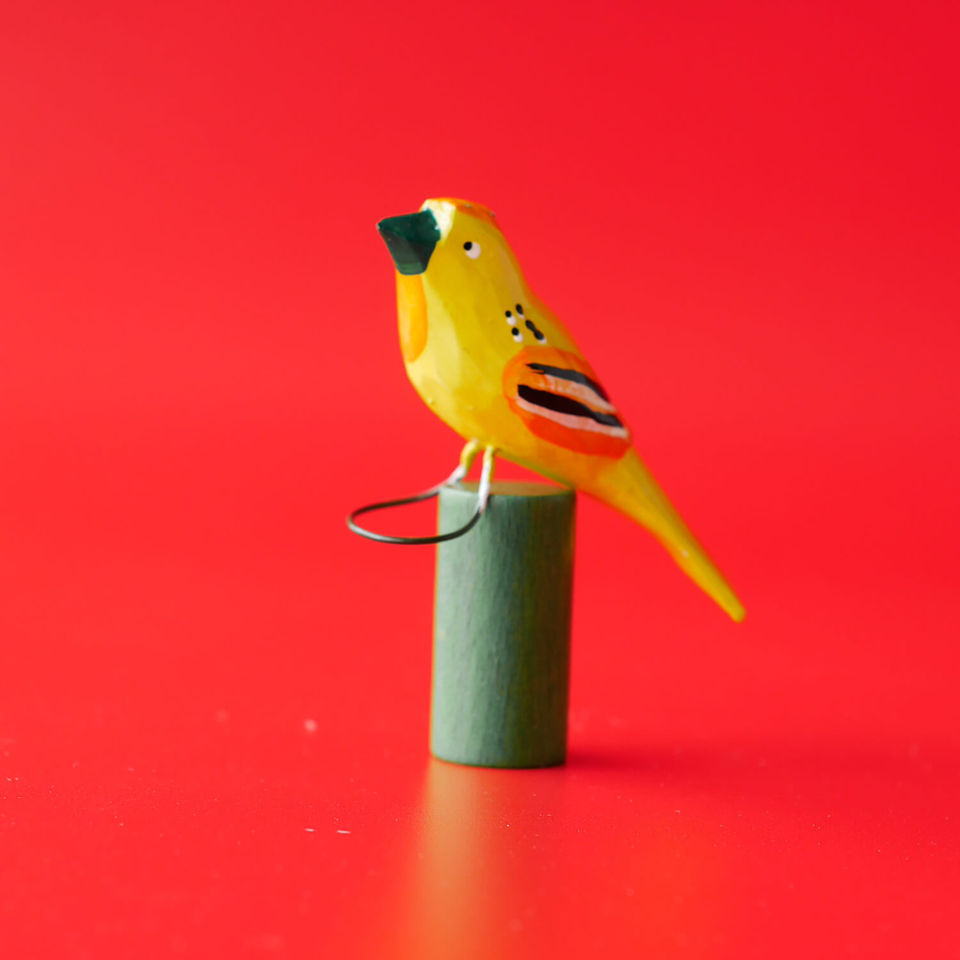 Hand-painted yellow bird figurine on red background
