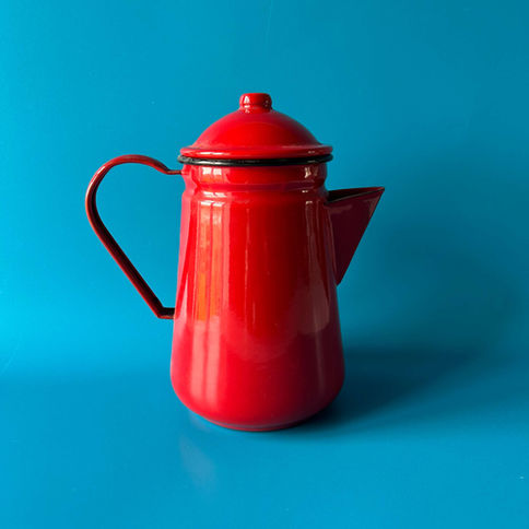 Red enamel coffee pot on blue background