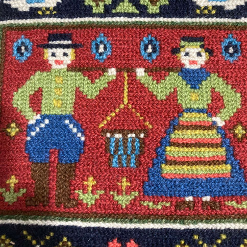 Hand-embroidered cushion depicting cross-stitch folk figures