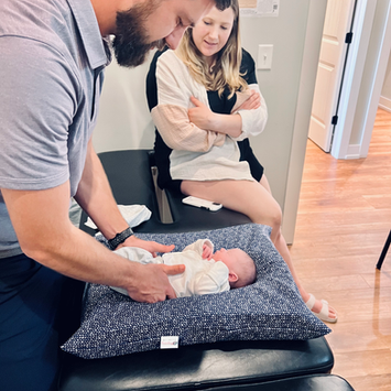 Chiropractor adjusting an infant while mom watches