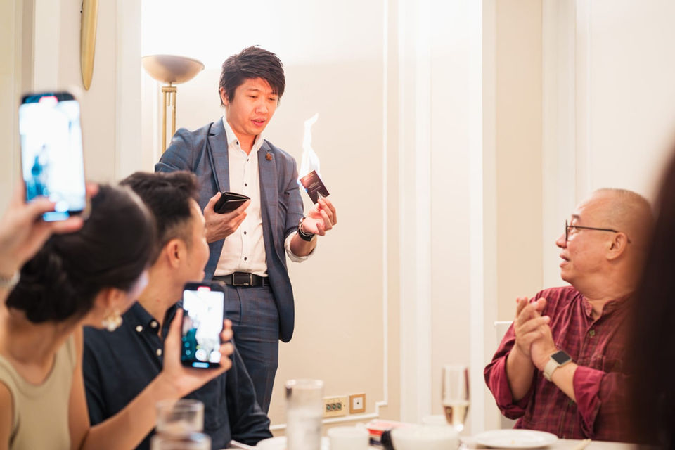 Magician performs fire card trick for guests