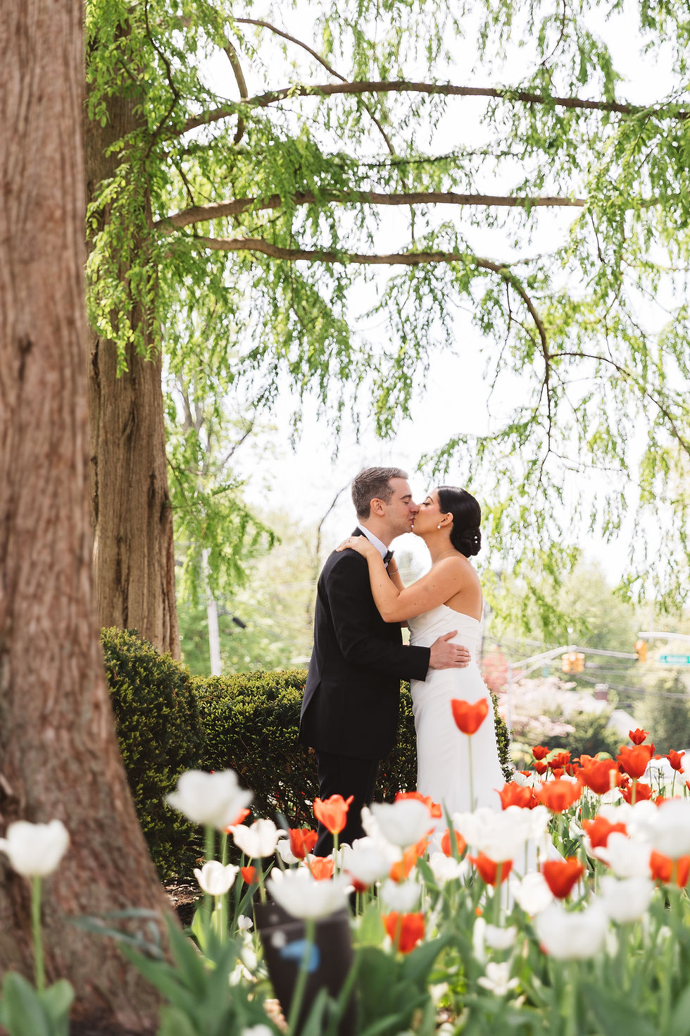 Bride and groom stand amongst bright tulips outside for their spring wedding day. Photographed at The Madison Hotel in Morristown, NJ by wedding photographer Madison Neumann Photography.