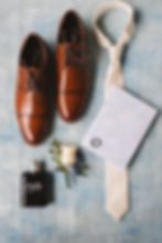 layout of groom's accessories including shoes, white tie, boutteniere, ring, vow booklet, and cologne bottle. Wedding day at Ash Mill Farm in Doylestown, PA. Photographed by South Jersey, Philadelphia based wedding photographer Madison Neumann Photography.