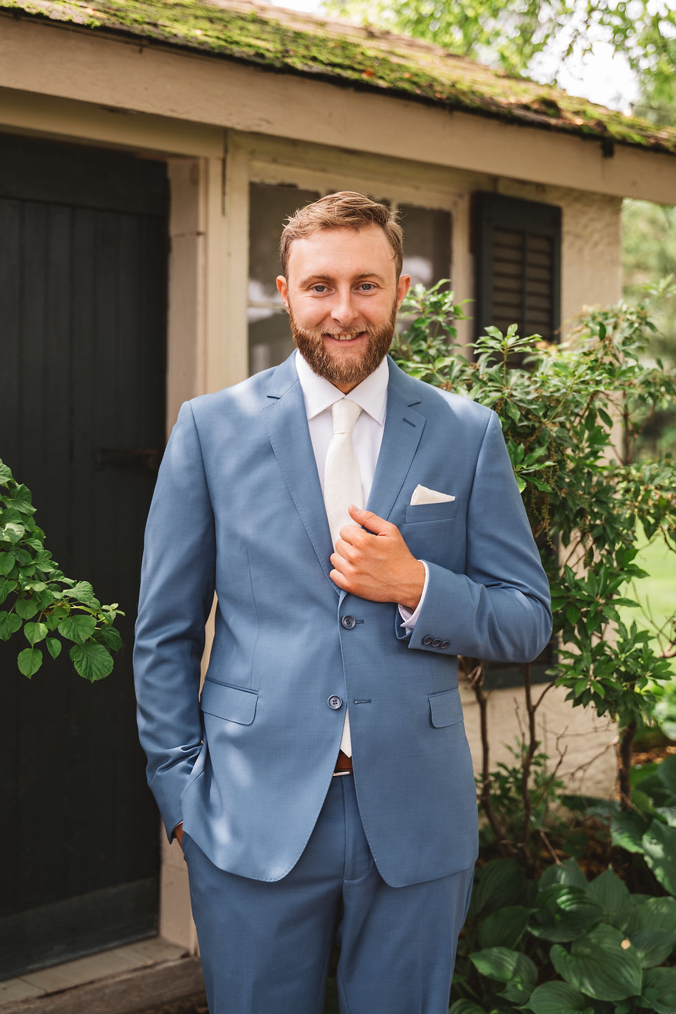 Groom smiles dressed in blue suit and white tie. Wedding day at Ash Mill Farm in Doylestown, PA. Photographed by South Jersey, Philadelphia based wedding photographer Madison Neumann Photography.