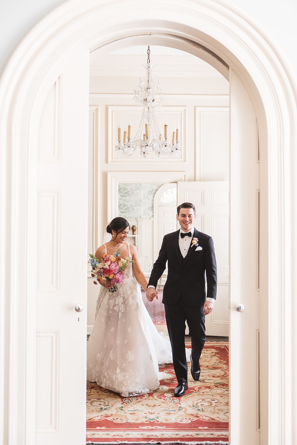 Bride and groom smile and hold hands as they walk through the halls together. Wedding day at Bellevue Hall in Wilmington, DE. Photographed by South Jersey, Philly based wedding photographer Madison Neumann Photography.