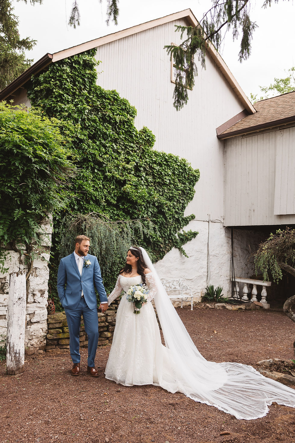 Newlywed bride and groom hold hands outside of farm barn venue. Wedding day at Ash Mill Farm in Doylestown, PA. Photographed by South Jersey, Philadelphia based wedding photographer Madison Neumann Photography.