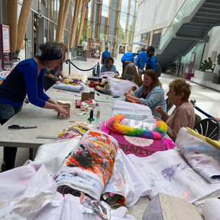 People joining community banners together at a long table inside the Herbert in Coventry