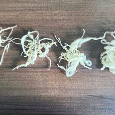 Sequential wool yarn samples produced during day two of spinning practice using wool fibre on an Ashford Traveller spinning wheel in temporary accommodation. The four samples document visible progression through irregular yarn formation, overtwist, slubs, interruption and increasing continuity as understanding of drafting, twist regulation and embodied learning developed through the Irregular Thread project.