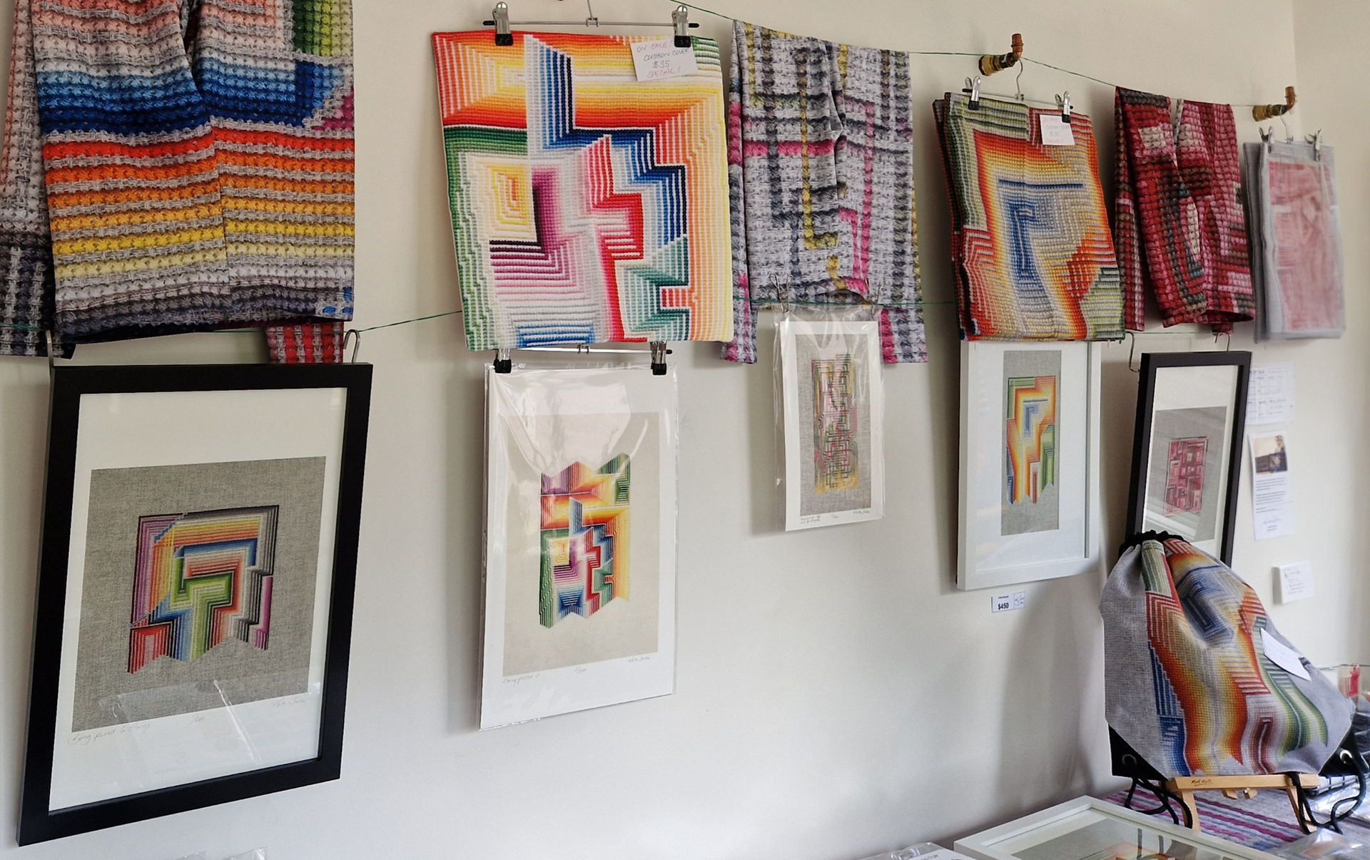 Hand stitched cross stitch pieces exhibited on a white wall