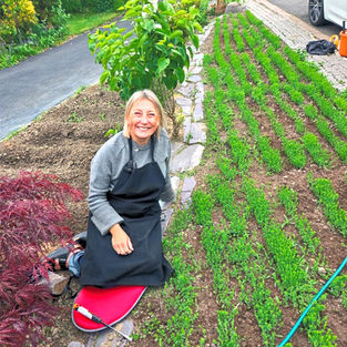 Amanda Haran kneeling beside rows of flax growing in her front garden in Riddings, Derbyshire.