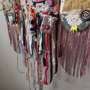 Close detail of the lower edge of Phoenix From The Bin showing pink sequin fringe, ribbons and hanging found objects.