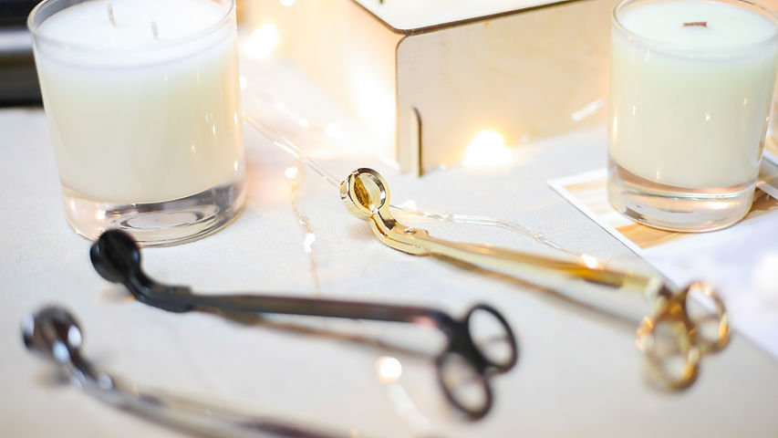 Wick golden, black, silver metal scissors for extinguishing white aroma candles in glass cups are ly