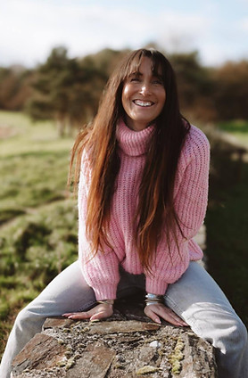 Portrait de Pauline 22h22, souriante, entourée par la nature pour accompagner la page "Contact"