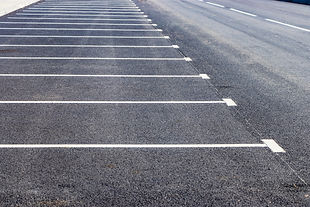 An empty parking lot in a residential area with yellow parking stops for cars