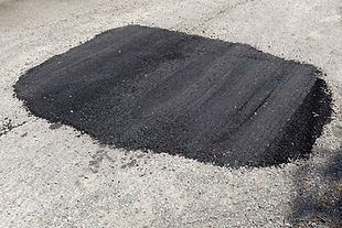 New asphalt repair of pothole on city street