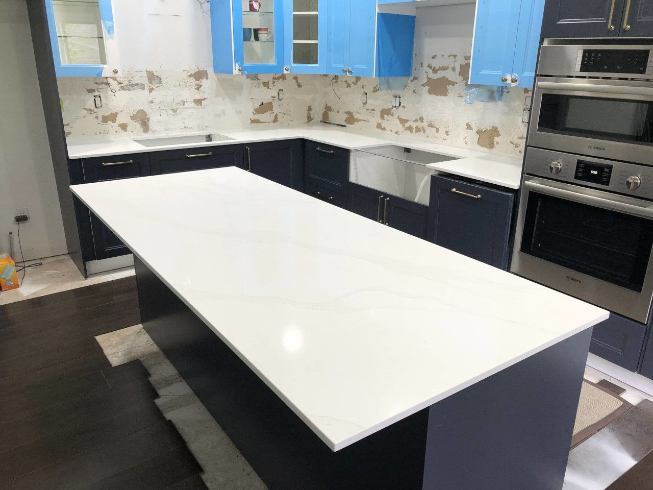 An unfinished kitchen project with well-polished countertops and blue cabinets
