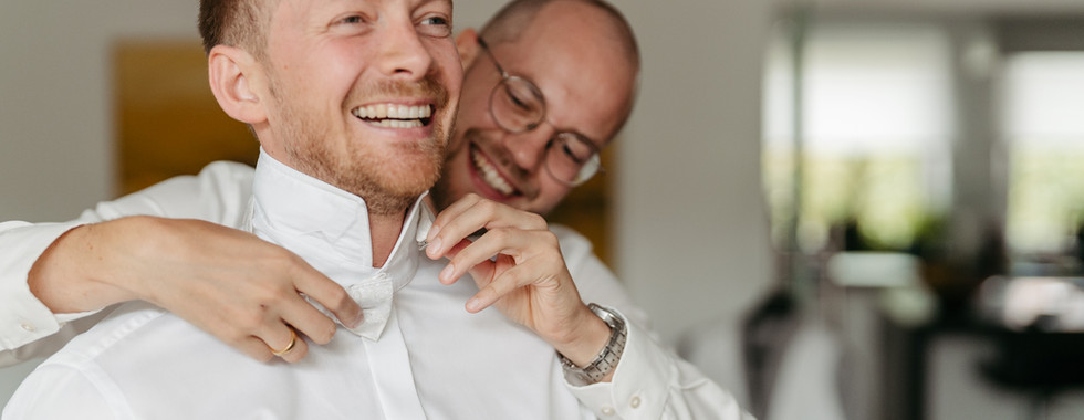 Trauzeuge hilft dem Bräutigam mit der Fliege