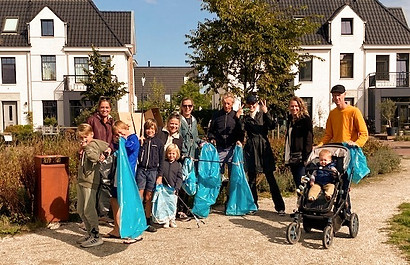 Groep mensen houden afvalknijpers en afvalzakken vast
