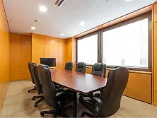 大きな窓から自然光が入る札幌ビレッジの重厚感ある会議室。革張りのチェアと大型テーブルを備えたビジネス向けミーティングルーム。
