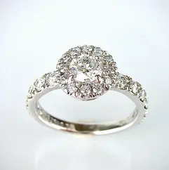 ラウンドブリリアントカットのセンターダイヤを中心に、パヴェセッティングのダイヤモンドがバンドに並ぶ、ホワイトゴールド製のハローエンゲージリング。