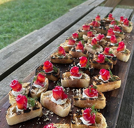 Delicious canapés on wooden board, outdoor setting