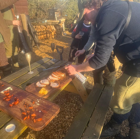 Person slicing charcuterie board outdoors