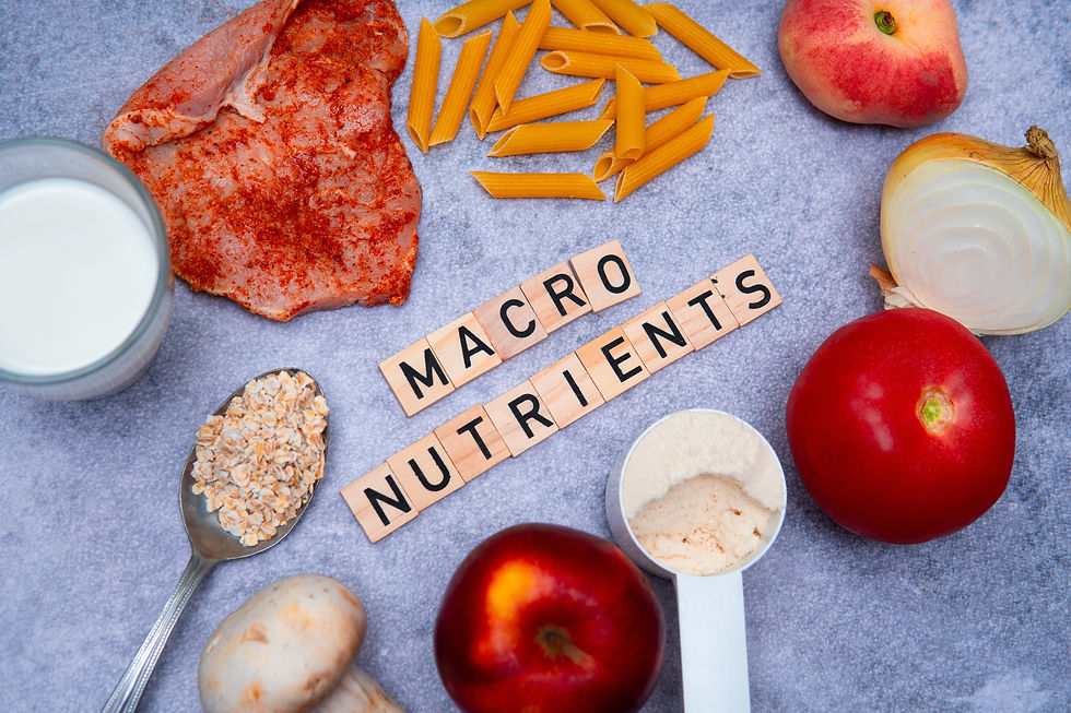 Various foods like pasta, milk, and meat surround wooden tiles spelling "MACRO NUTRIENTS" on a gray background. Bright and colorful display.