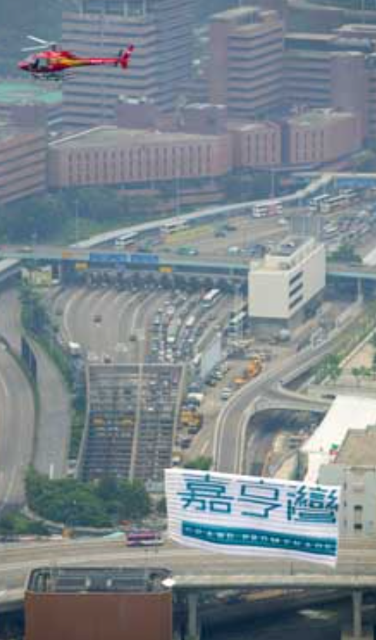 Eye-level view of a helicopter flying over a harbor with a large banner trailing behind