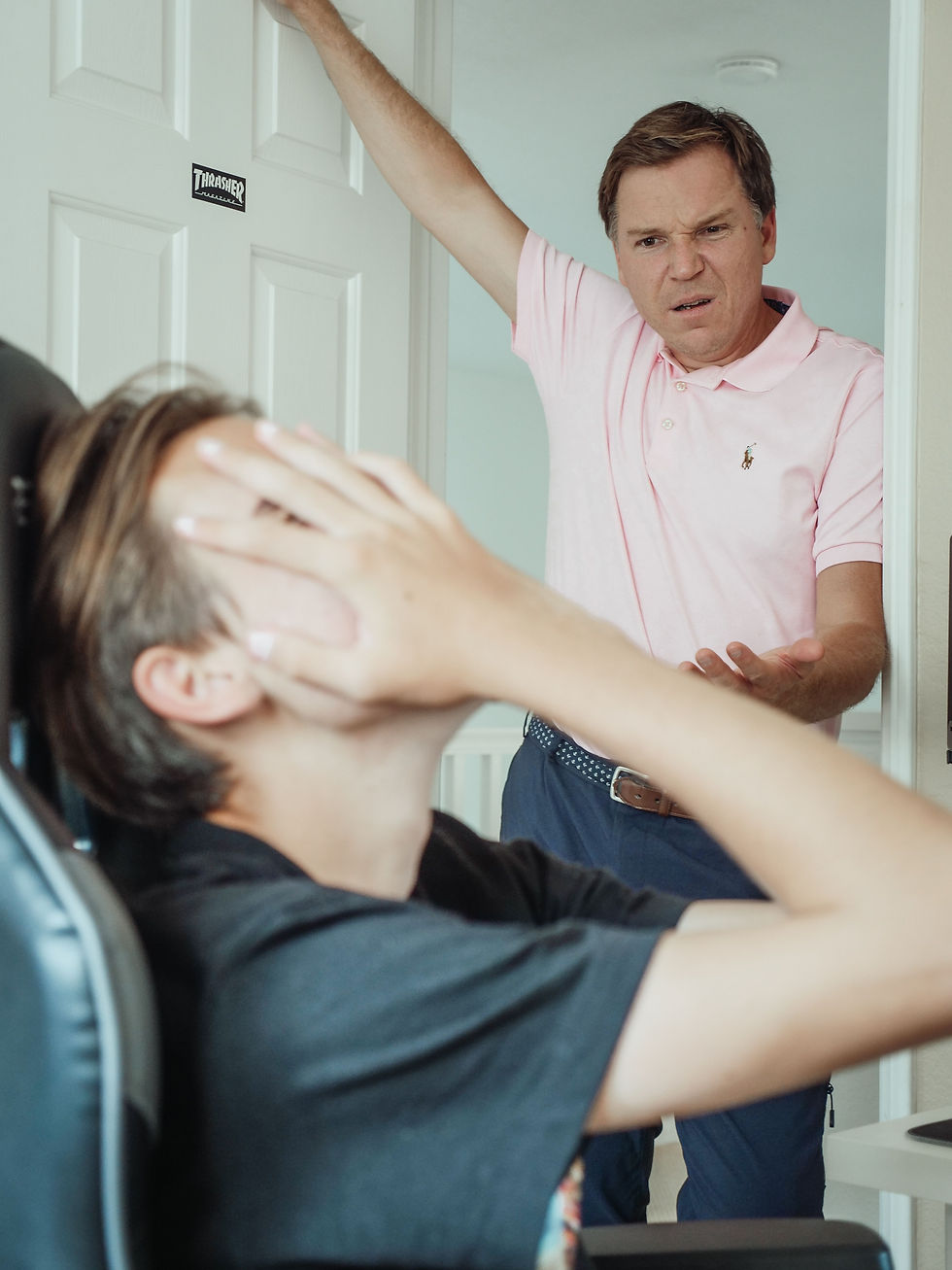 A father expresses frustration during a serious conversation, while a teenager appears overwhelmed, covering his face with his hands in response.