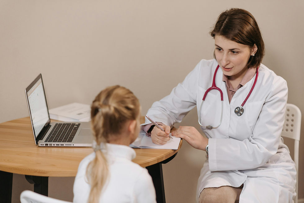A doctor engages in a caring consultation with a young patient, attentively listening and taking notes during their appointment.