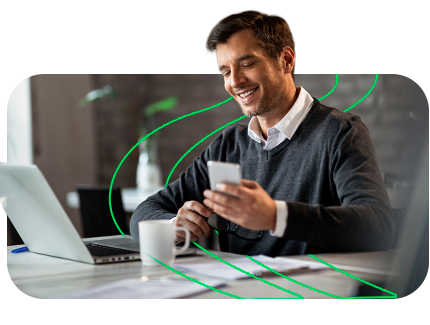 Homem sorridente usando smartphone em ambiente de trabalho com tecnologia.