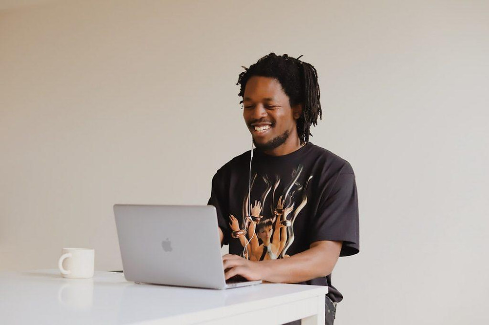 A smiling man working on a laptop.