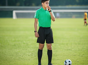 Young soccer referee at field blowing whistle.jpg