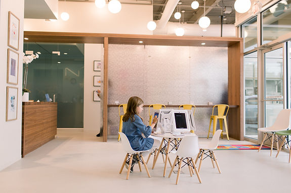 A pre-teen sits at a table of interactive games in the sun-soaked lobby of Dentini Houston Heights.