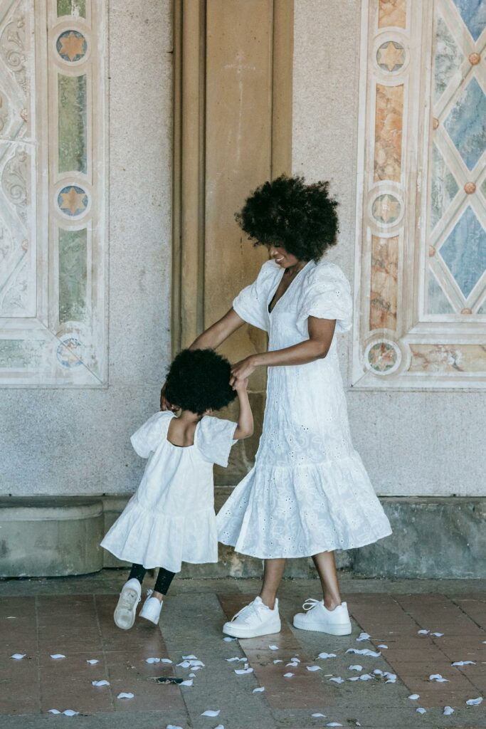 Photo by Barbara Olsen : https://www.pexels.com/photo/a-woman-and-a-girl-in-white-dresses-dancing-on-a-floor-with-flower-petals-7879721/