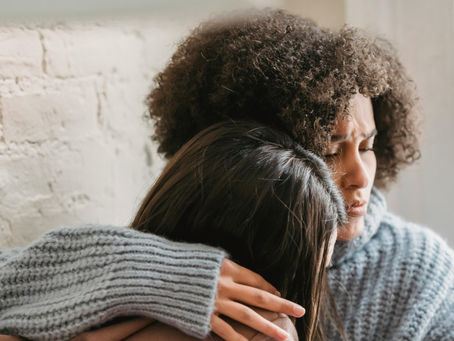 Eine Person hält eine andere im Arm und spendet Trost.