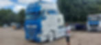 A man washing a blue DAF truck with a pressure washer, covering it in white foam