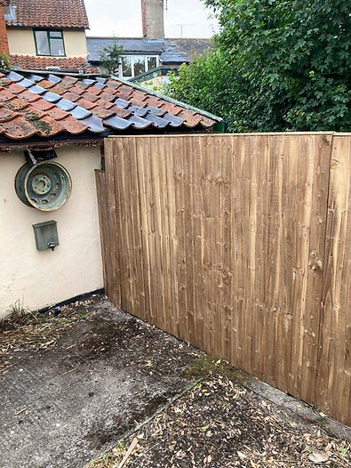 Wooden fence with vertical planks abruptly ending against a pale wall